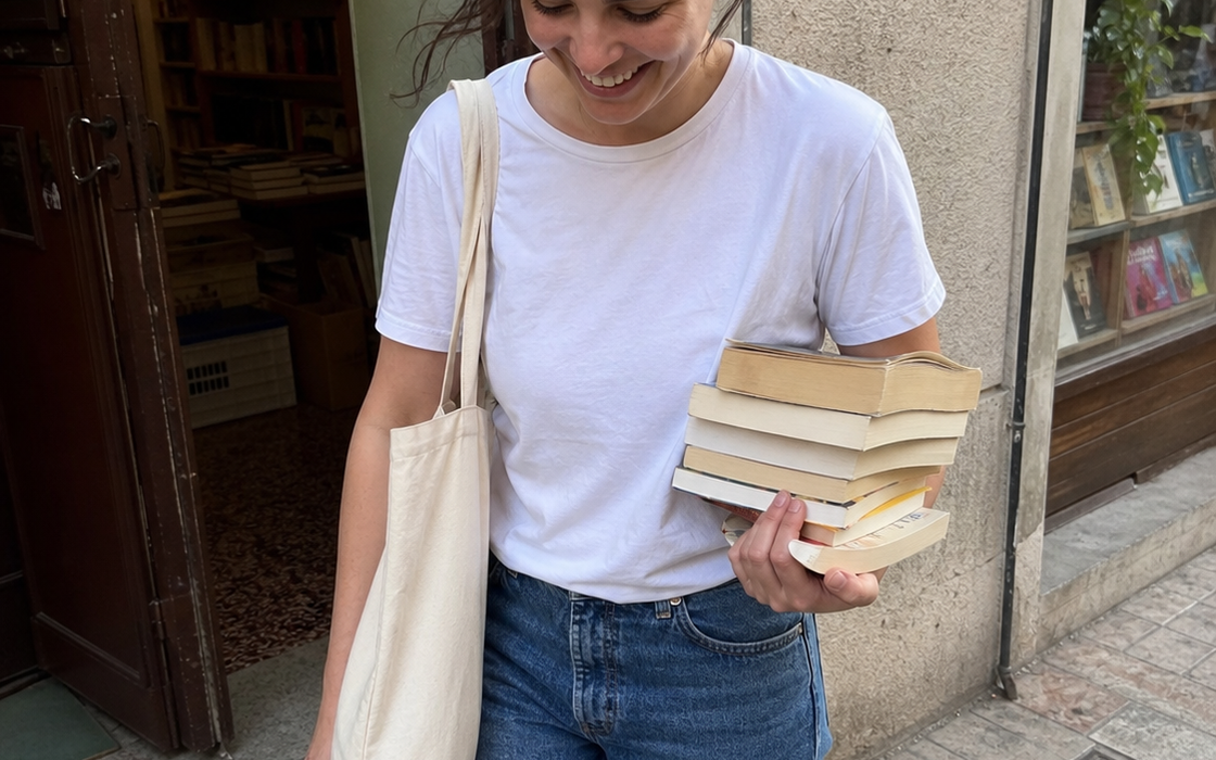 Frau mit Stofftasche und Büchern vor einer Buchhandlung – editoriale OBELLU Bildwelt