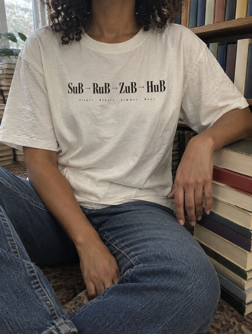 Nahaufnahme des Shirt-Drucks SuB zu RuB zu ZuB zu HuB zwischen Büchern