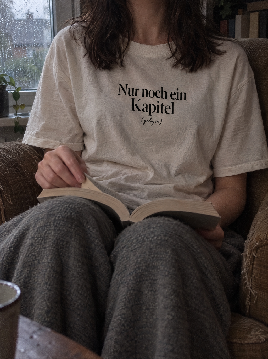Nahaufnahme des Shirt-Drucks Nur noch ein Kapitel (gelogen) im Sessel