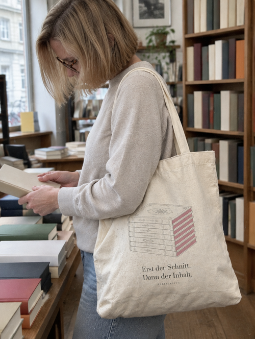 Frau trägt die Farbschnitt Tote-Bag in einer Buchhandlung, Erst der Schnitt. Dann der Inhalt.