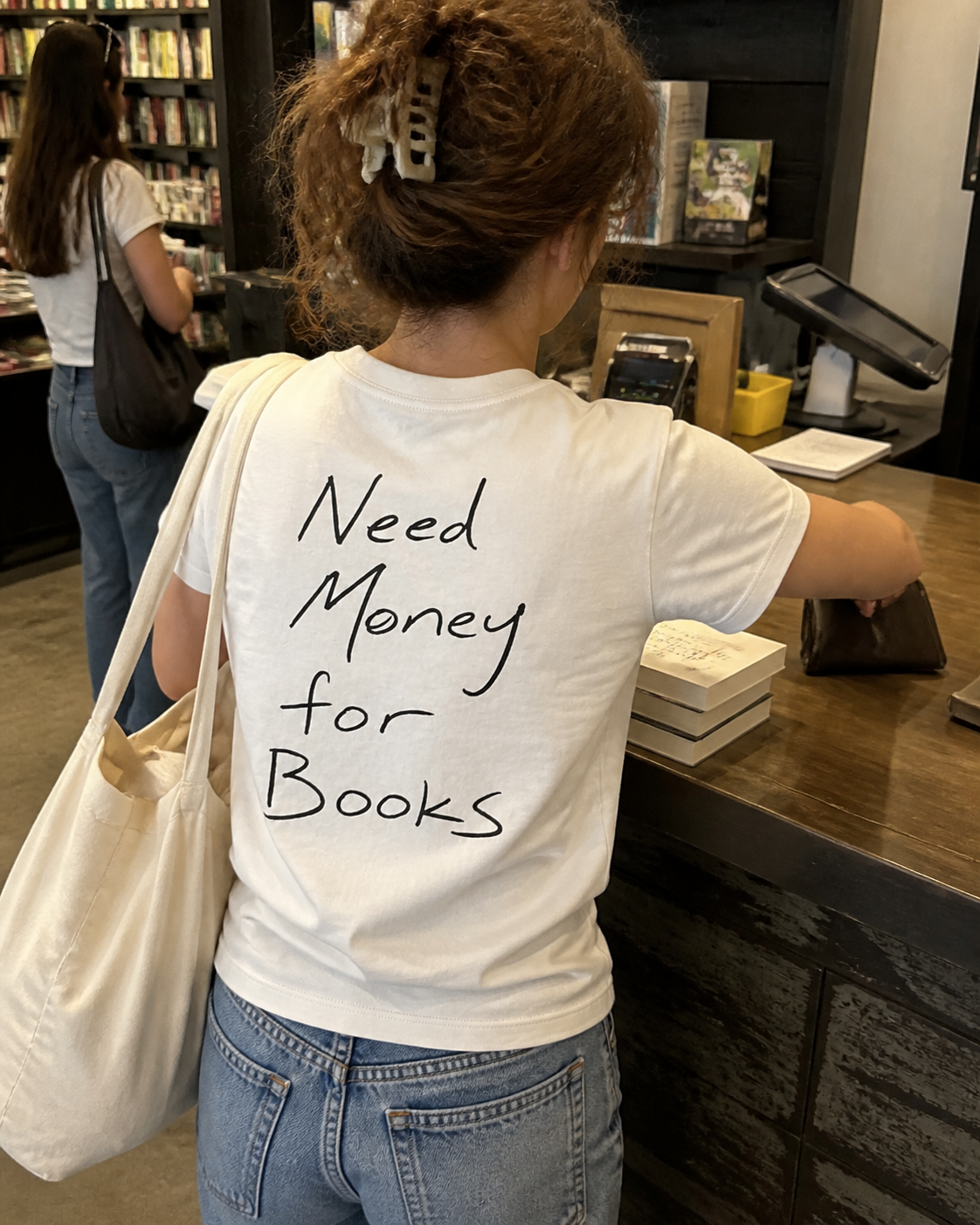 Need Money for Books Classic T-Shirt – editoriales Produktvisual an der Buchladenkasse